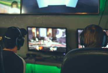 selective focus photography of two persons playing game in front of monitors